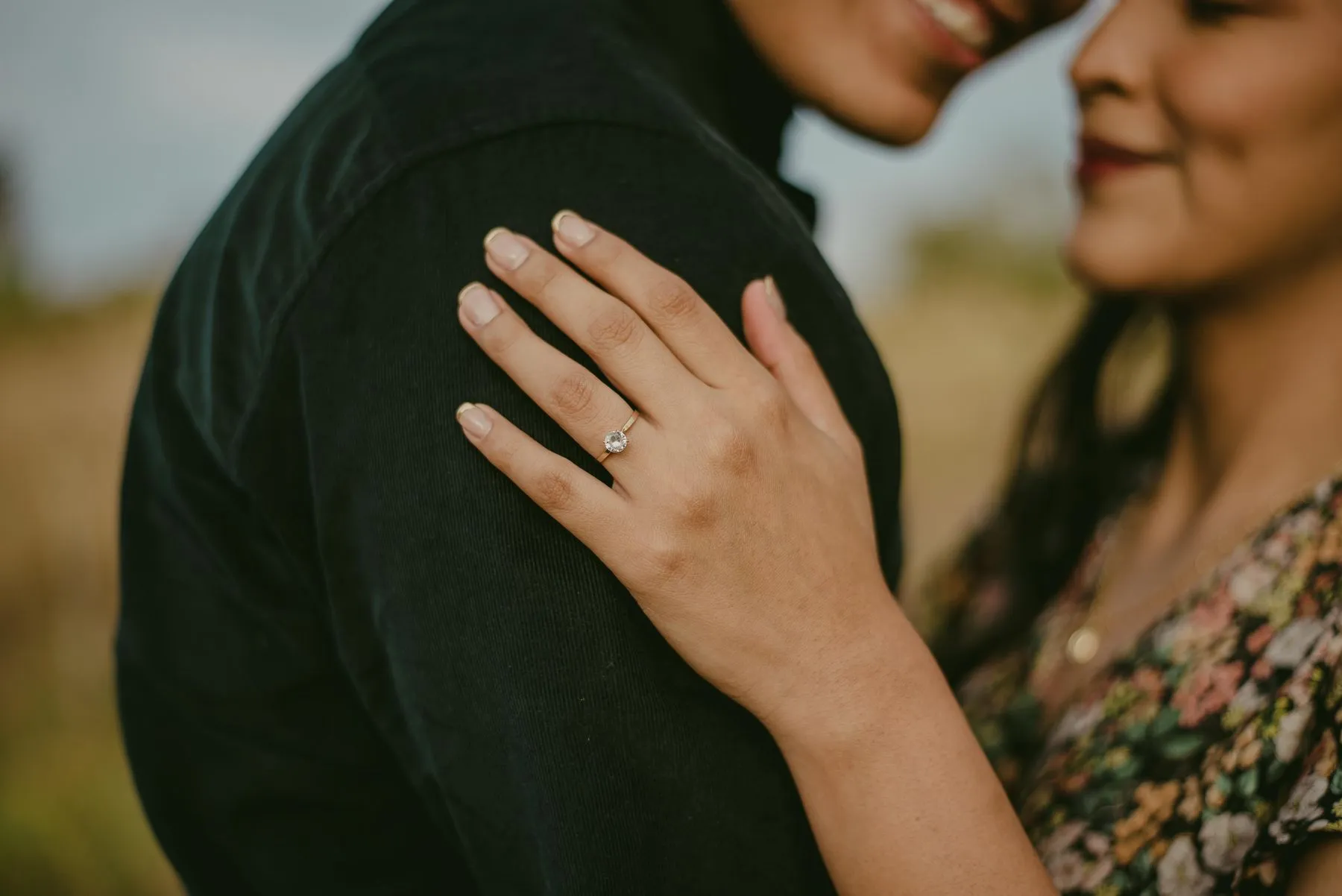 Engaged couple embracing and showing an engagement ring