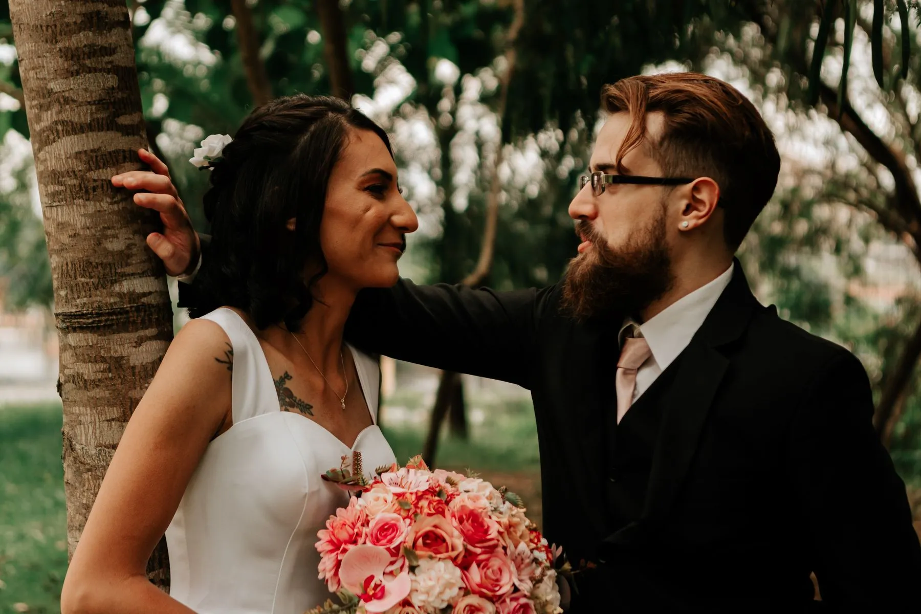 Wedding couple looking at each other beside greenery